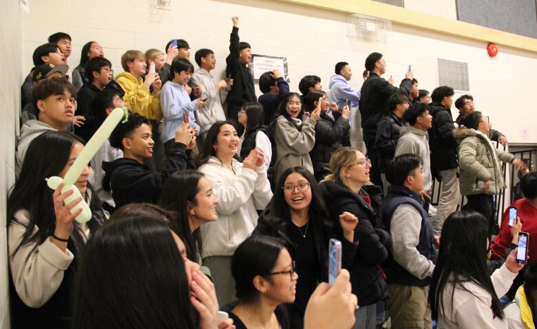 Dozens of cheering fans fill a set of bleachers at the school. They're cheering for their basketball team.