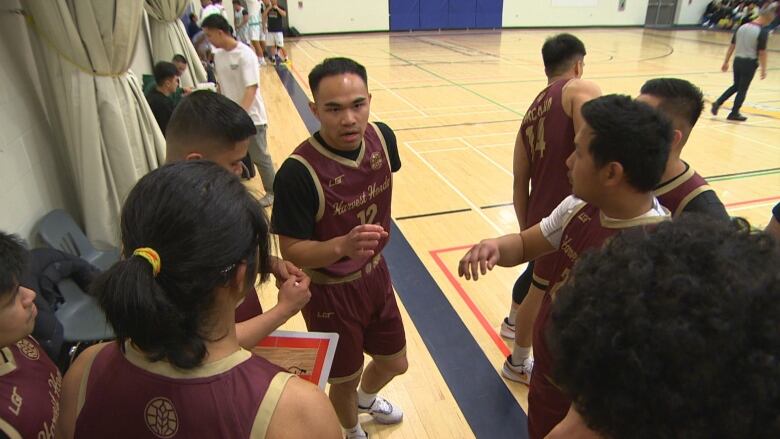 Abram Razon, centre, is in a huddle with his basketball team before they hit the court to start their game.