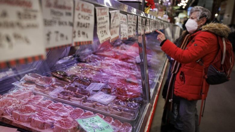 A man stands in front of a meat counter at an indoor market.