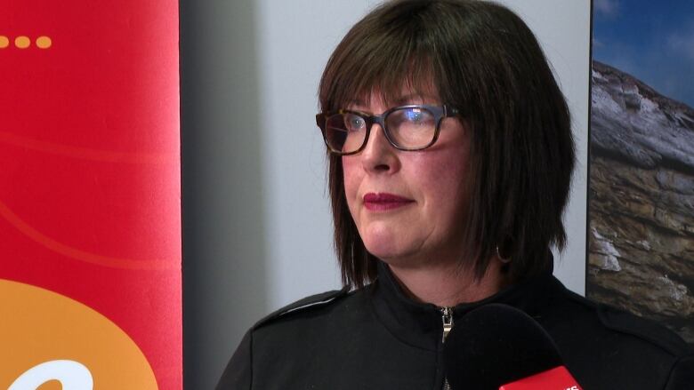 A woman wearing a black shirt and glasses standing in front of a podium. 