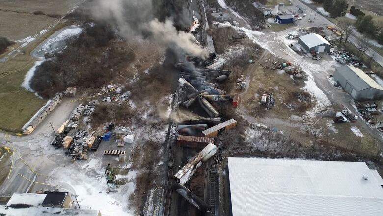 Burned and derailed freight cars are scattered around on the ground.