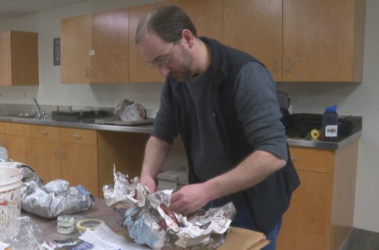 person unwrapping fossil 