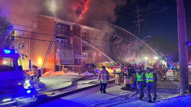 Firefighters blast water onto a burning three-storey apartment building.