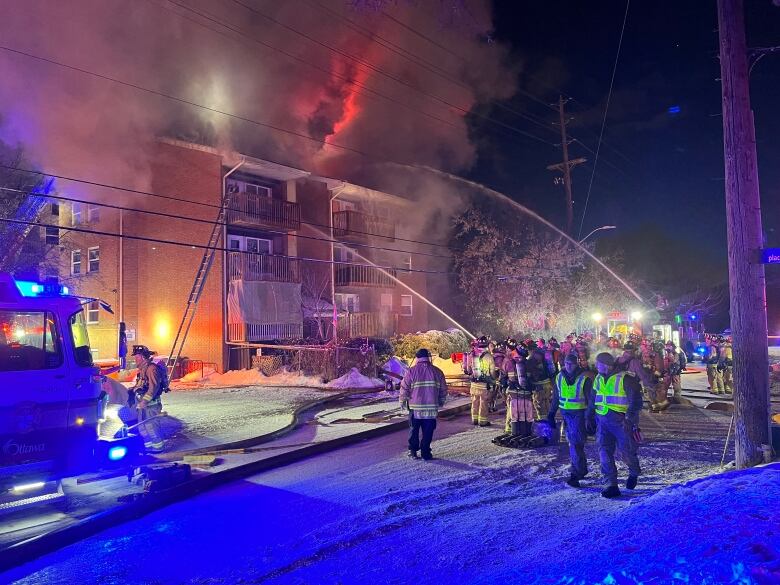 Firefighters blast water onto a burning three-storey apartment building.