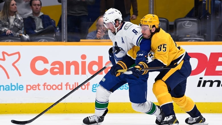 Vancouver Canucks centre J.T. Miller, left, with the puck, attempting to hold off Nashville Predators centre Matt Duchene.