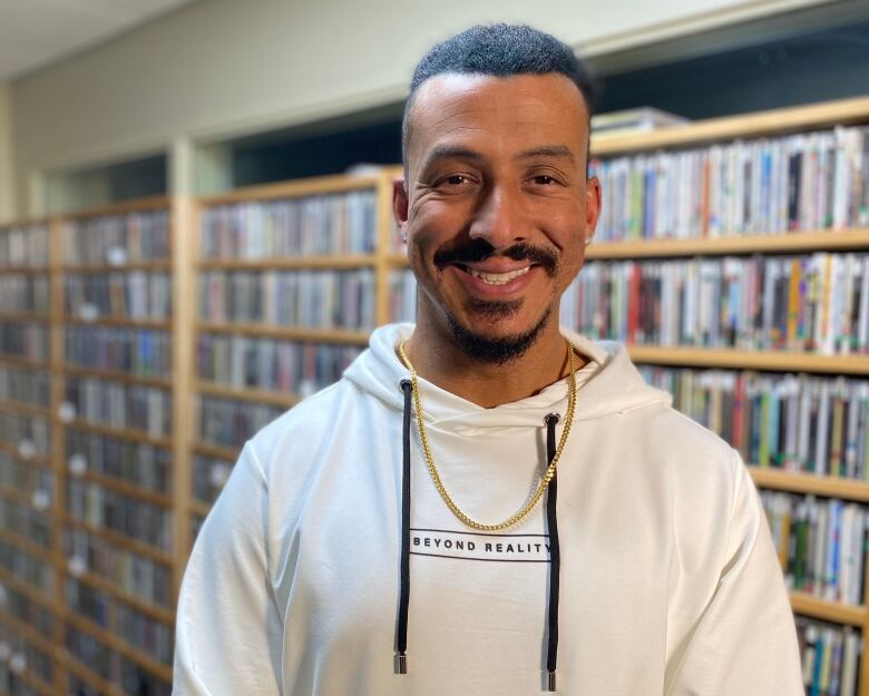 A man with a goatee smiles while looking into the camera. He is wearing a hooded sweatshirt that says Beyond Reality. 