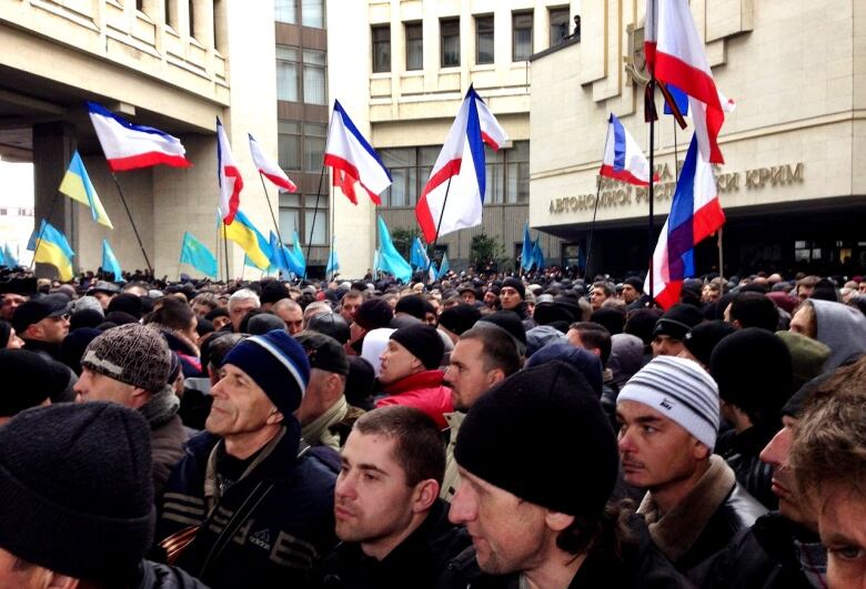 People protest outside parliament in Crimea, waving flags from Ukraine and Russia.