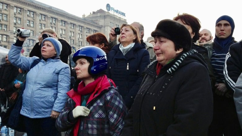 People stand together in a public square, grieving.