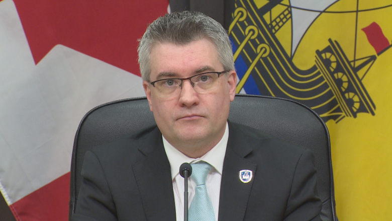 A man sitting in front of a Canadian and New Brunswick flag