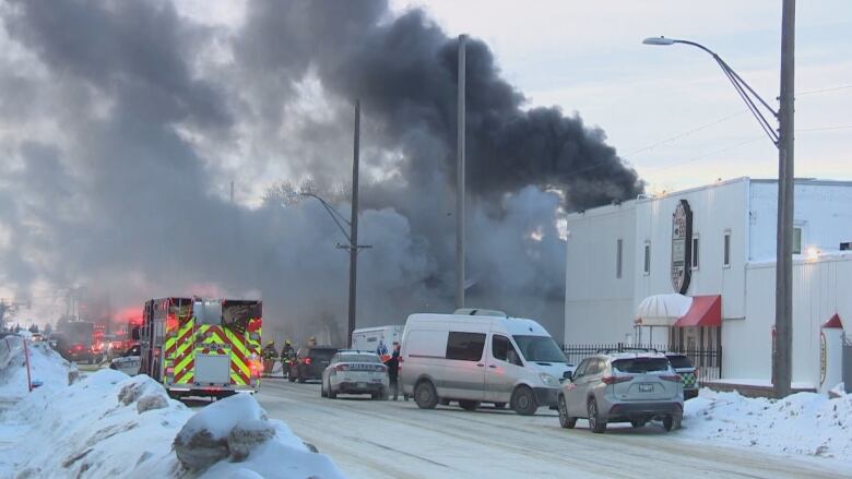 Smoke shoots out of a structure, blocking off a stretch of traffic.