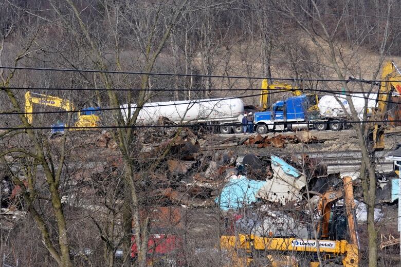 Large trucks and railyard debris are shown.