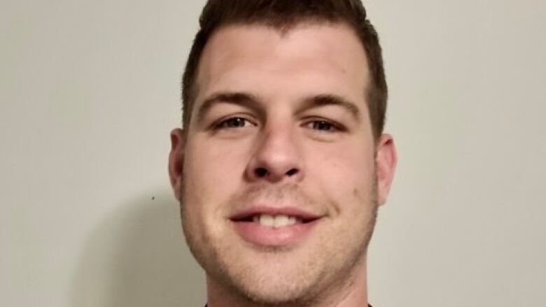 A man with short hair and facial hair smiles at the camera.