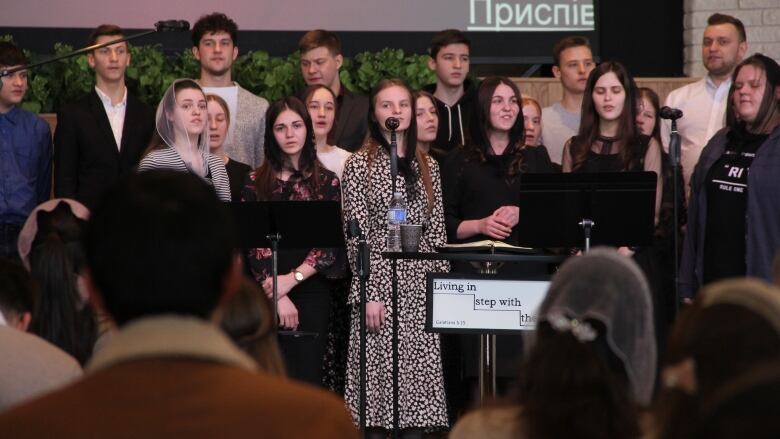 A choir stands at the front of a church and sings.