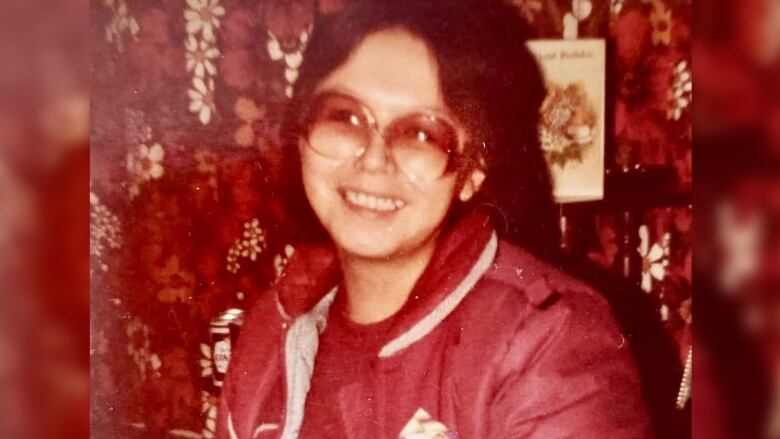 An old portrait of a smiling woman in dark sunglasses.