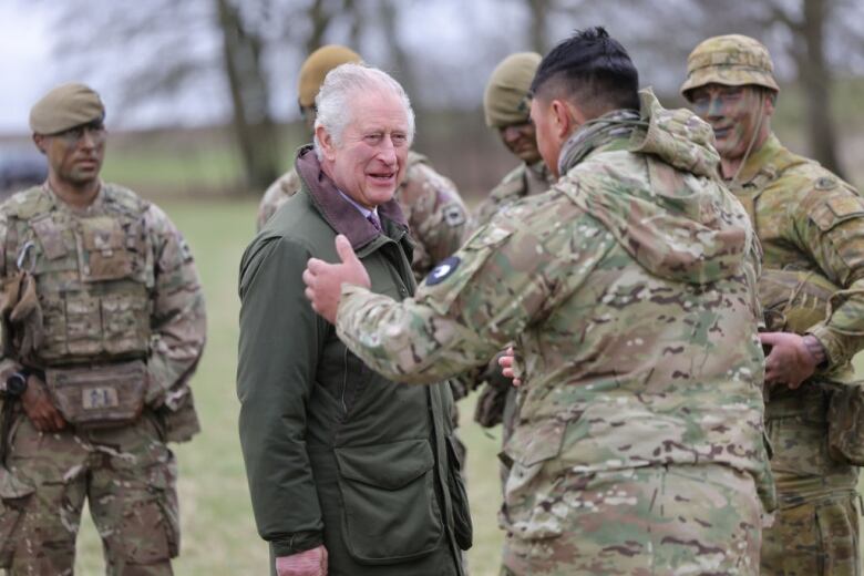 Several people in military attire speak with another person.