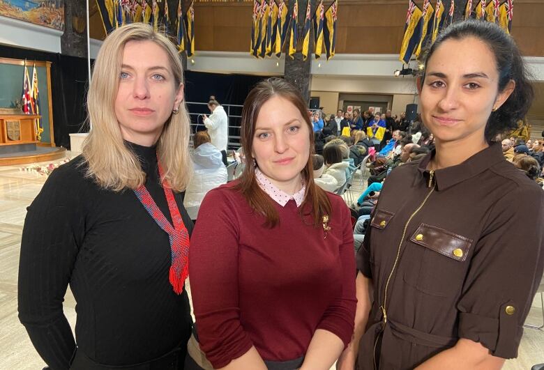 Three women look into the camera.