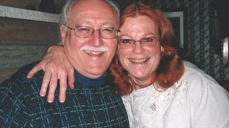 A man and woman smile at the camera for a photo.