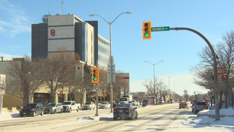 A downtown Steinbach street with a vehicle driving through the intersection in the foreground.