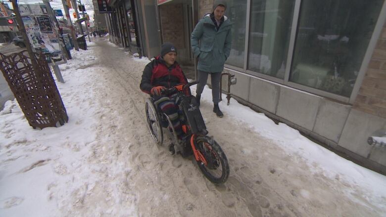 Accessibility advocate Russell Winkelar operates his chair on a snow-covered sidewalk.