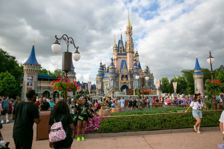 People walk in front of a castle-like structure at a theme park. 