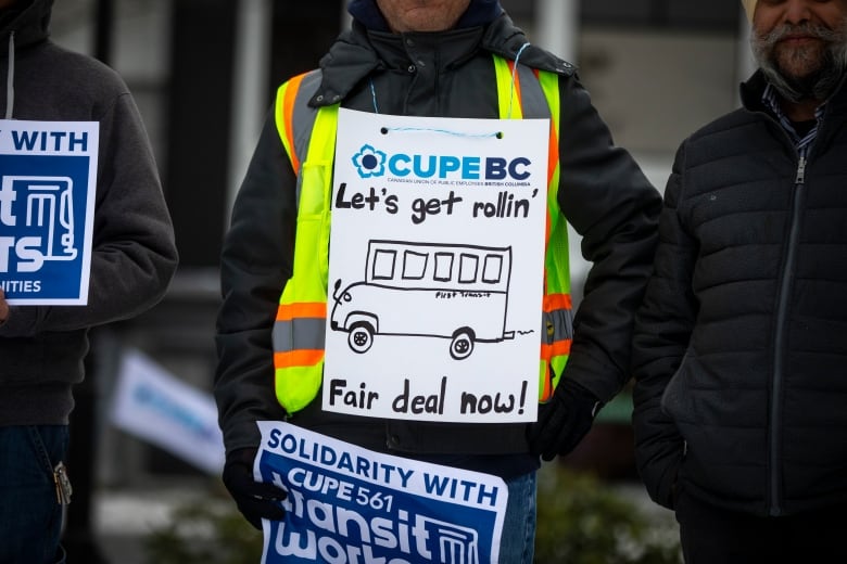 A worker on strike wears a sandwich board sign that says 