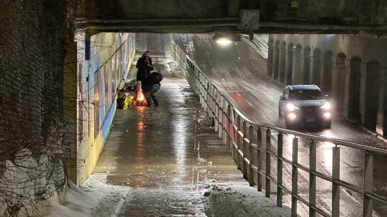 Unhoused Londoners stay warm by a makeshift fire pit under the Richmond Street train overpass between York and Horton Streets in London, Ont.