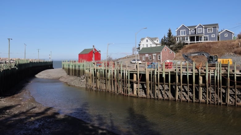 A mound of gravel sits in the water at the entrance to a harbour. 