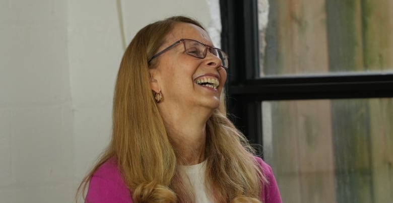 A woman laughing to something behind the camera. 