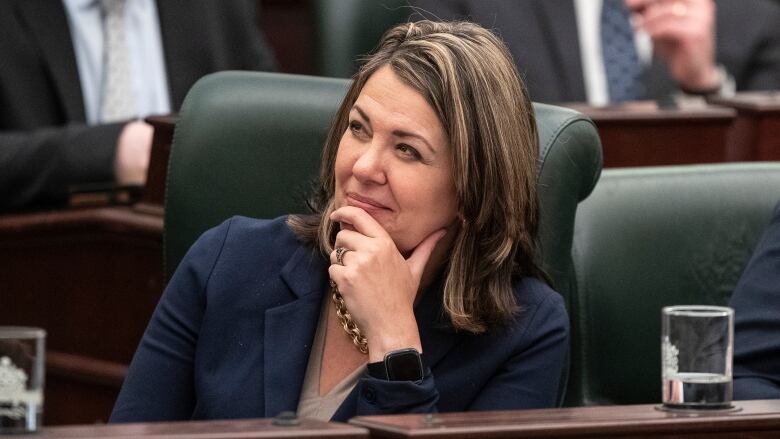 Danielle Smith smiles with her hand on her chin.