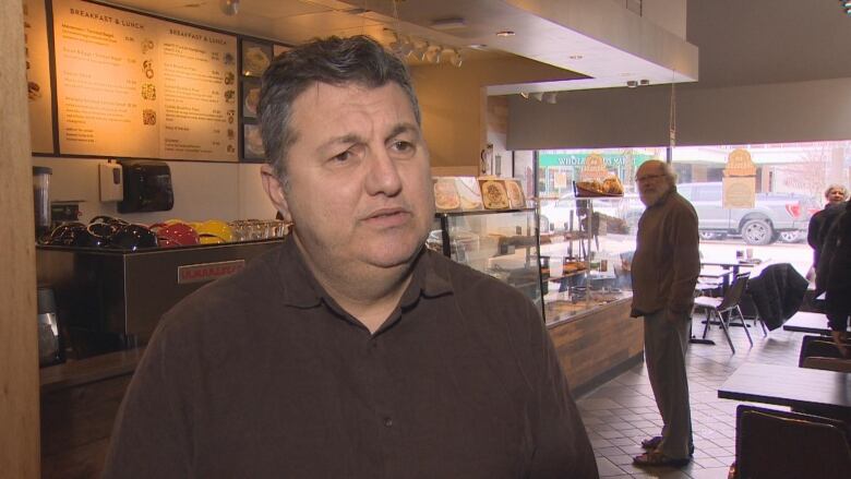 A man stands in front of a bakery case 