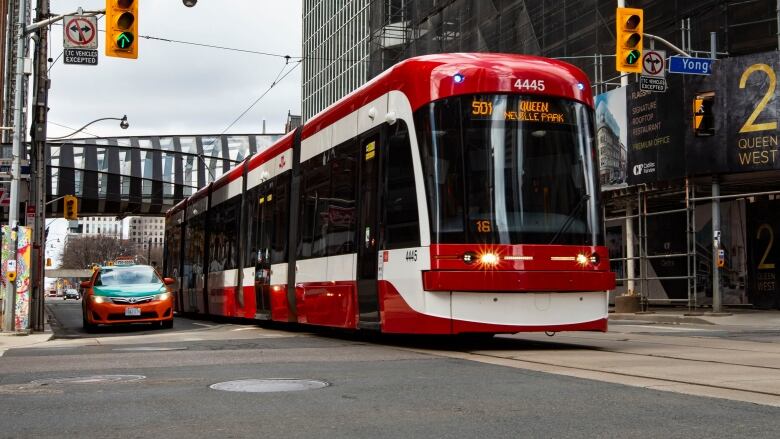 a red and white streetcar crosses an intersection.