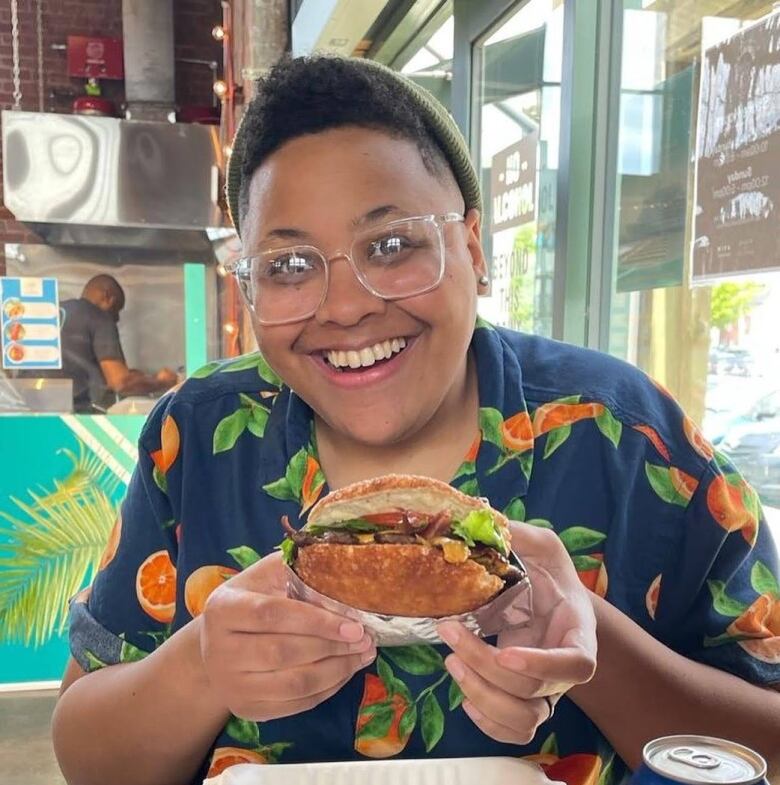 A woman holds up a sandwich.