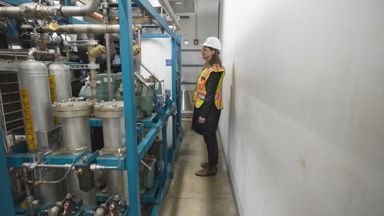 A woman in safety gear looks at pipes in the chiller room