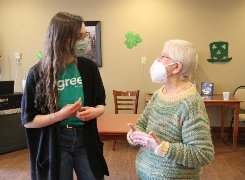 Woman in green t-shirt talkes to an older woman.