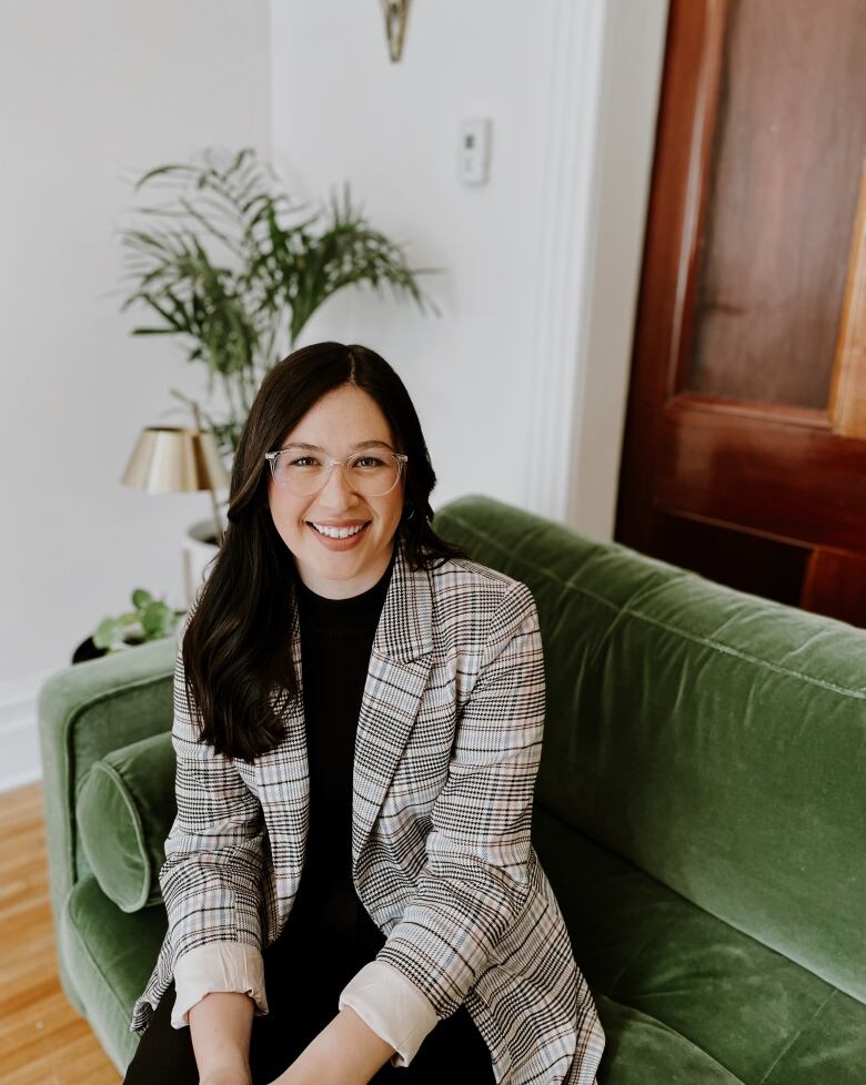 A woman with long dark hair sits on a green couch.