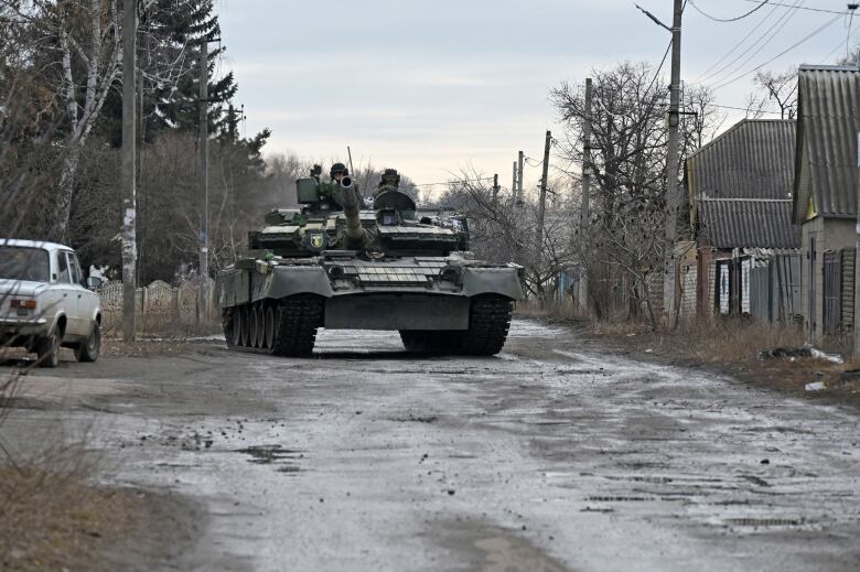 A Ukrainian tank is seen driving through a village in Kharkiv region on Friday.