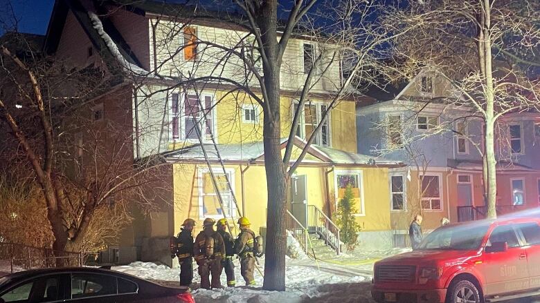 A group of firefighters are pictured standing in front of a home.