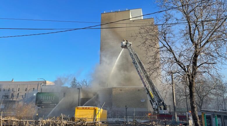 A hose from above sprays a building on fire.