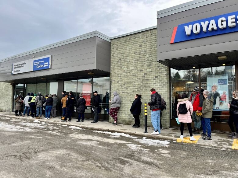 More than a dozen people lined up outside an SAAQ office. 