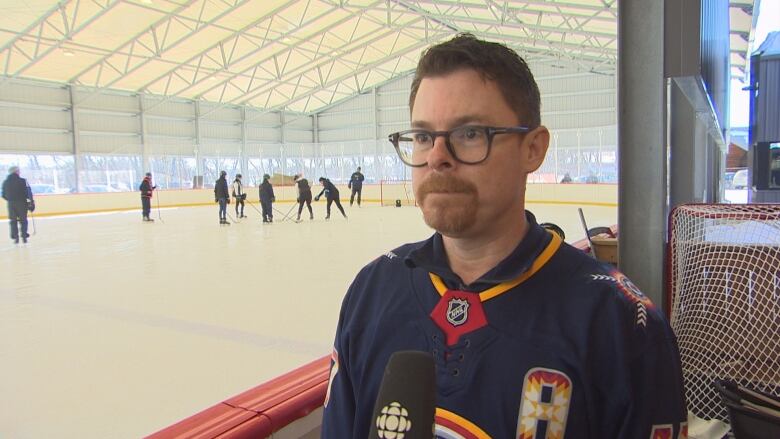 A man in a Winnipeg Jets jersey by a sheet of ice in rural Manitoba.