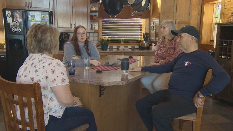 A group of four adults sit around a table