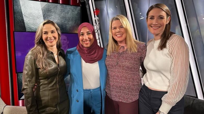 Four women stand arm in arm.