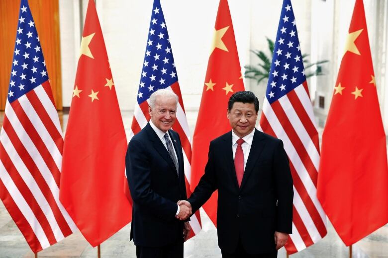 The Chinese President Xi Jinping shakes hands with U.S. VP Joe Biden in front of flags.