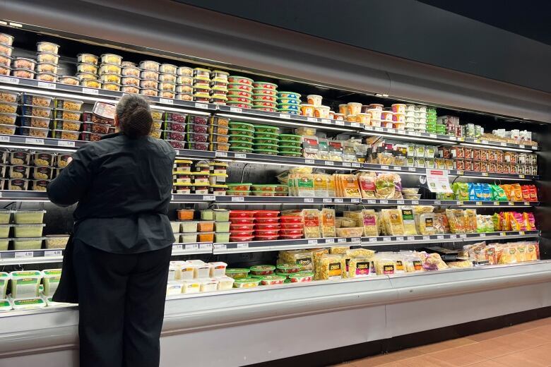 A woman stocks shelves at a grocery store.