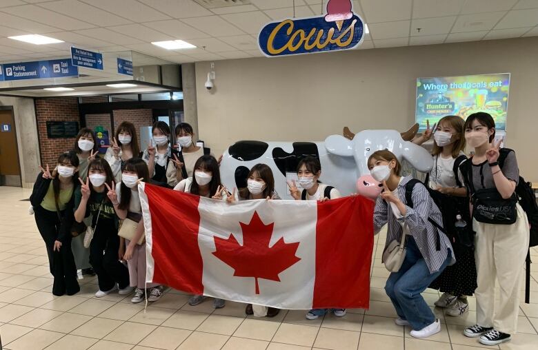 Japanese students pose with cow statue.