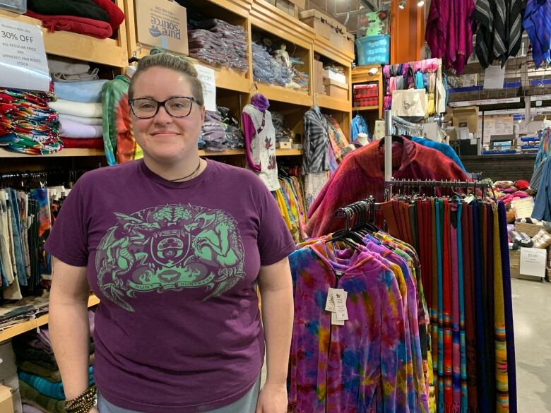 Woman standing in front of colorful shirts.