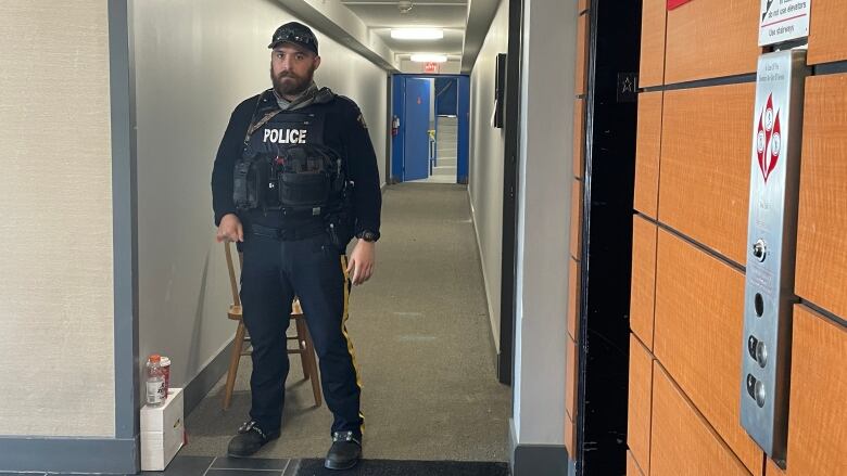 A police officer stands in an apartment hallway.