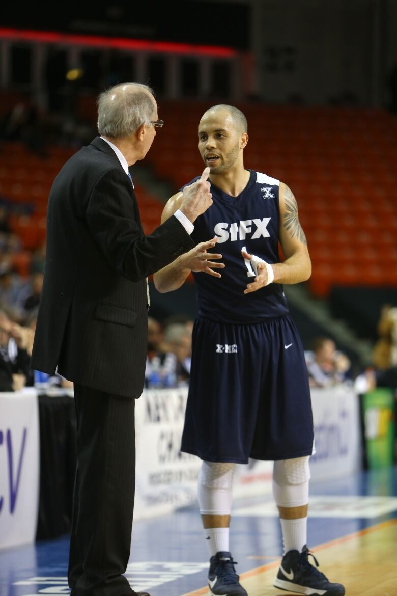 A basketball coach gives direction to his player during a time-out. 