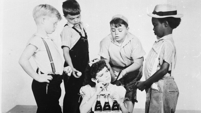 Four boys and girl are shown in a black and white photo from several decades ago.