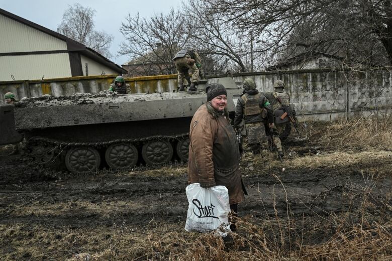 An elderly woman looks on as Ukrainian soldiers prepare to move to the front line near the city of Bakhmut.